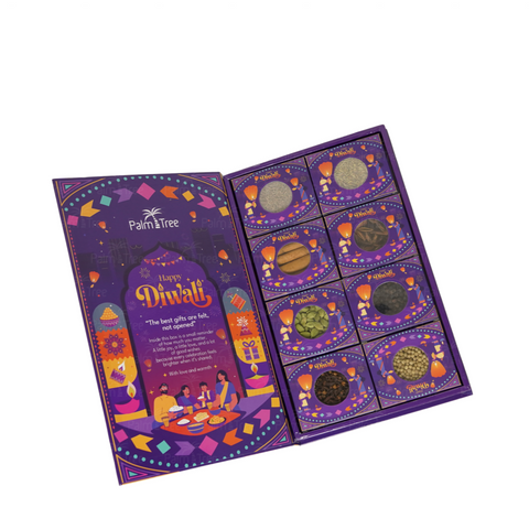 Palm Tree Happy Diwali gift set in a purple box, shown open to reveal 12 small decorative packets containing colorful powder and spice blends, with a larger illustrated packet on the left.